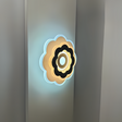 Modern Flower LED Wall Light in a sleek flower shape, crafted from metal and acrylic, fixed on a white wall, emitting soft, warm white light.