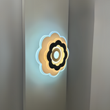 Modern Flower LED Wall Light in a sleek flower shape, crafted from metal and acrylic, fixed on a white wall, emitting soft, warm white light.
