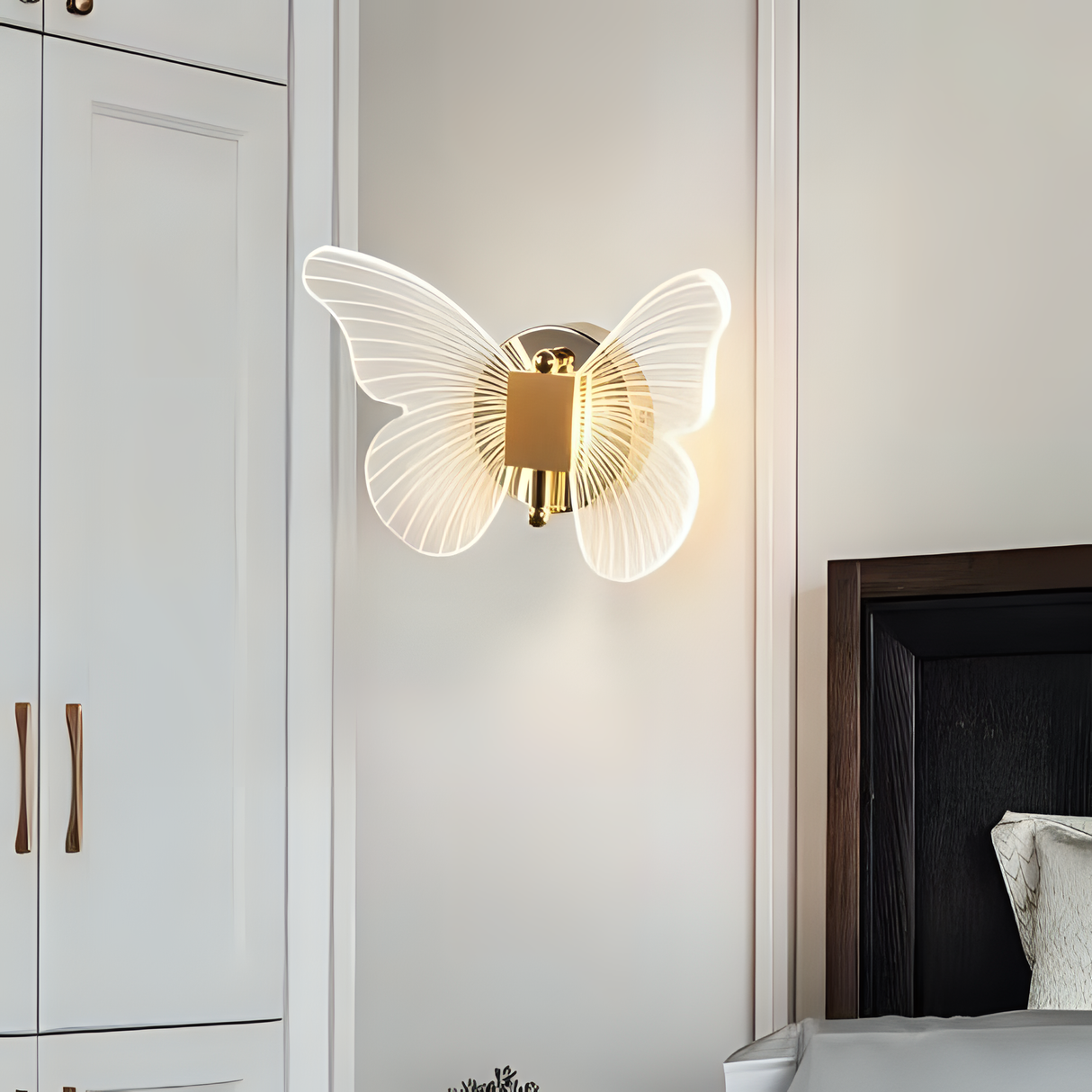 A unique butterfly-shaped wall sconce with a gold circular base, featuring two illuminated frosted glass wings that create a soft and elegant glow.
