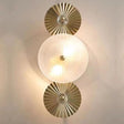 A stylish dual-wall sconce with circular, pleated white glass diffusers and gold accents, mounted on a beige wall.
