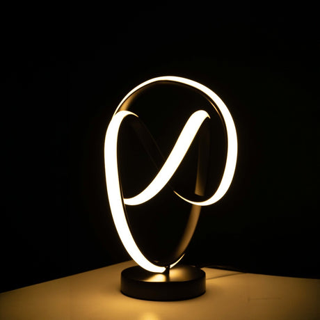 The LED table lamp has a black base with intertwined infinity-loop shapes. The loops are lit up with soft white light, creating a glowing effect. it sits  on  a wooden table with dark background