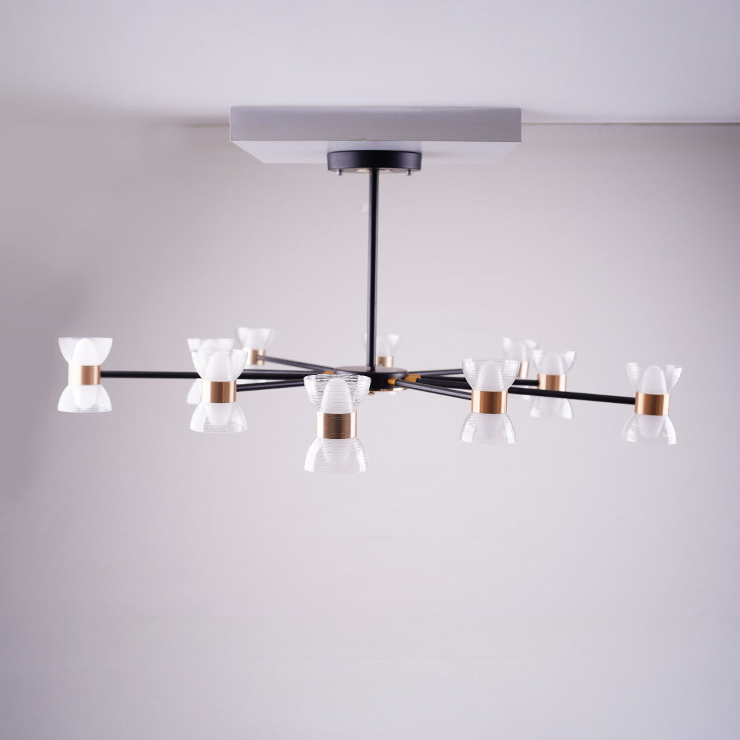 A sleek black chandelier with multiple arms, each holding a small white conical glass shade, mounted on a square ceiling base in a minimalist setting.