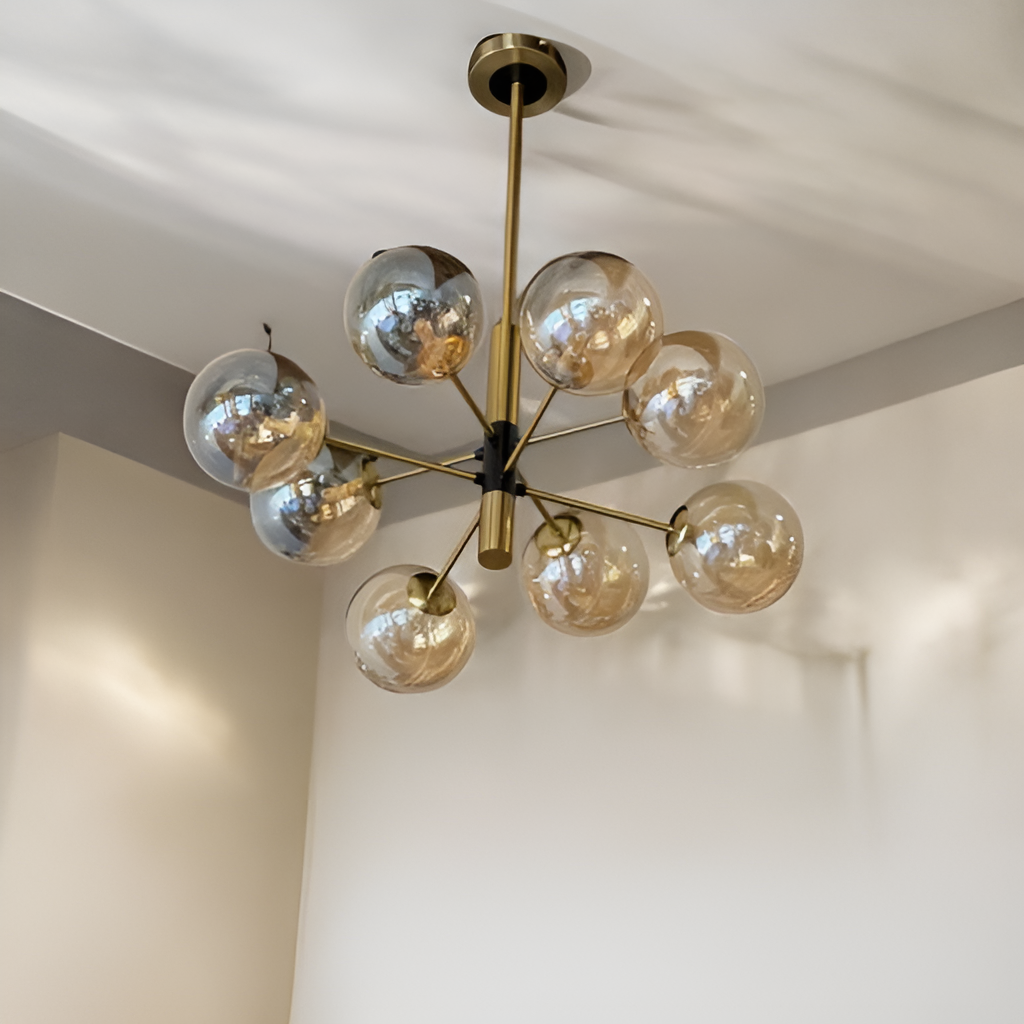 A gold and black chandelier with multiple glass globe bulbs, fixed to a white ceiling.