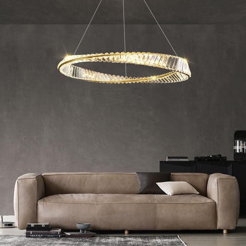 A modern gold and crystal circular chandelier hanging in a living room with a beige couch in the background.