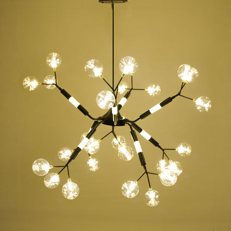 Modern starburst-style chandelier with multiple crystal-glass bulb covers on black and gold arms, emitting warm white light. 