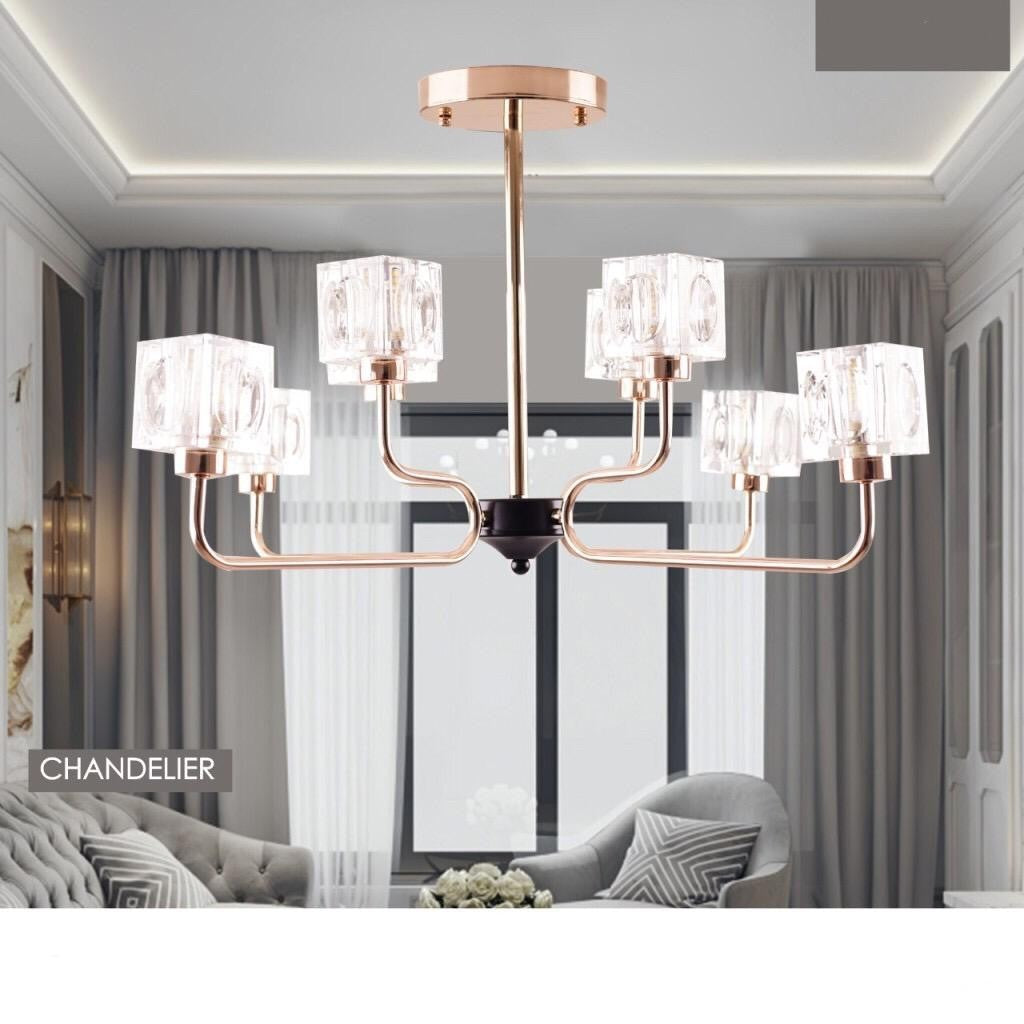 A modern chandelier with a rose gold metal frame and multiple cubic glass light covers in a living room setting.