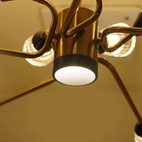 Close-up of a gold modern chandelier with cylindrical arms and  glass light covers, showcasing a central matte black fixture base.