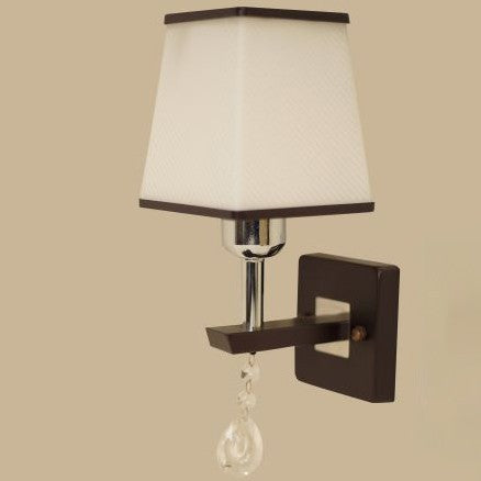 A brown and silver wall light with a rectangular fabric shade and a hanging crystal ornament, adding a touch of elegance.