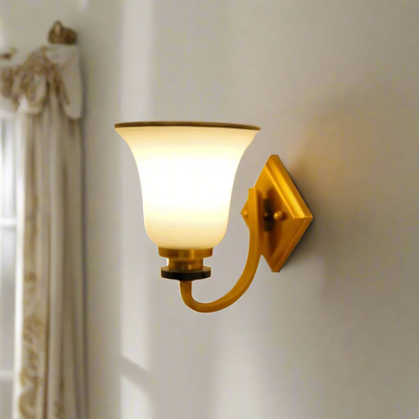 A metal wall sconce with a frosted glass shade, equipped with a led lamp e27 emitting warm illumination placed on a white wall 