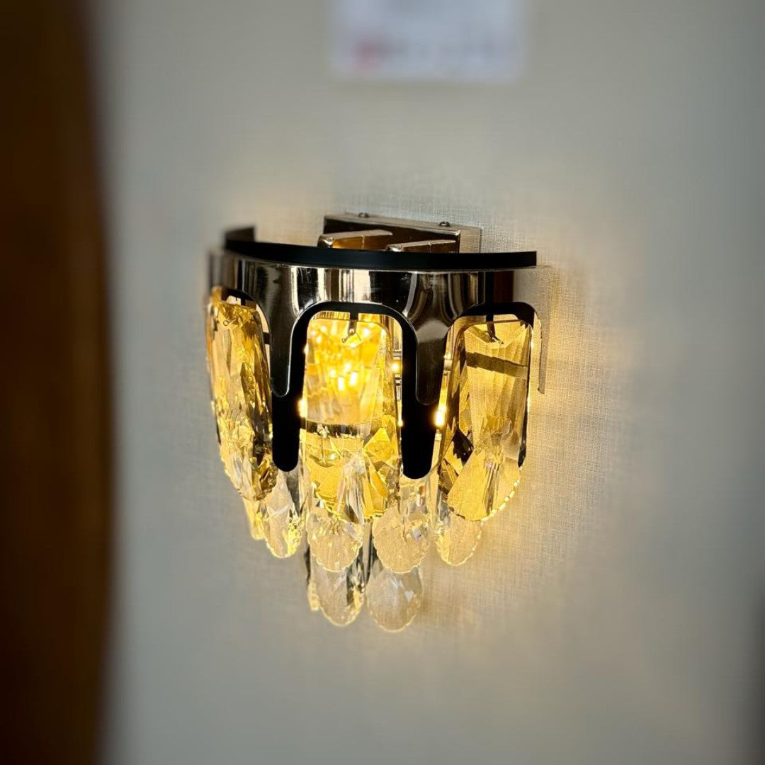 A contemporary gold wall light with delicate crystal elements, beautifully illuminating the space with a soft, golden light.
