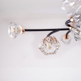  A close-up view of a modern light fixture with black curved arms and diamond-shaped glass bulbs.