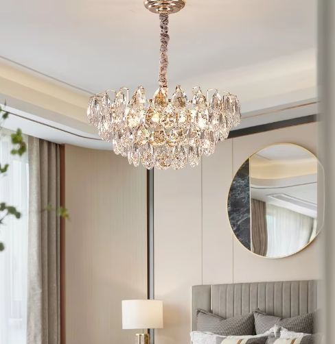 Chandelier hanging above a bed in a bedroom with a mirror and lamp.
