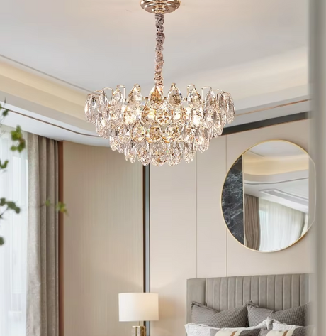 Chandelier hanging above a bed in a bedroom with a mirror and lamp.