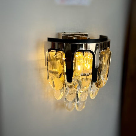 A contemporary gold wall light with delicate crystal elements, beautifully illuminating the space with a soft, golden light.