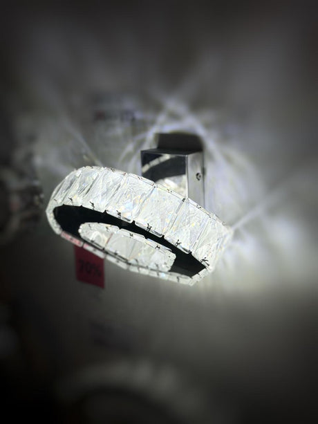 A circular crystal wall light with an elegant ring design, emitting a bright, luxurious glow.