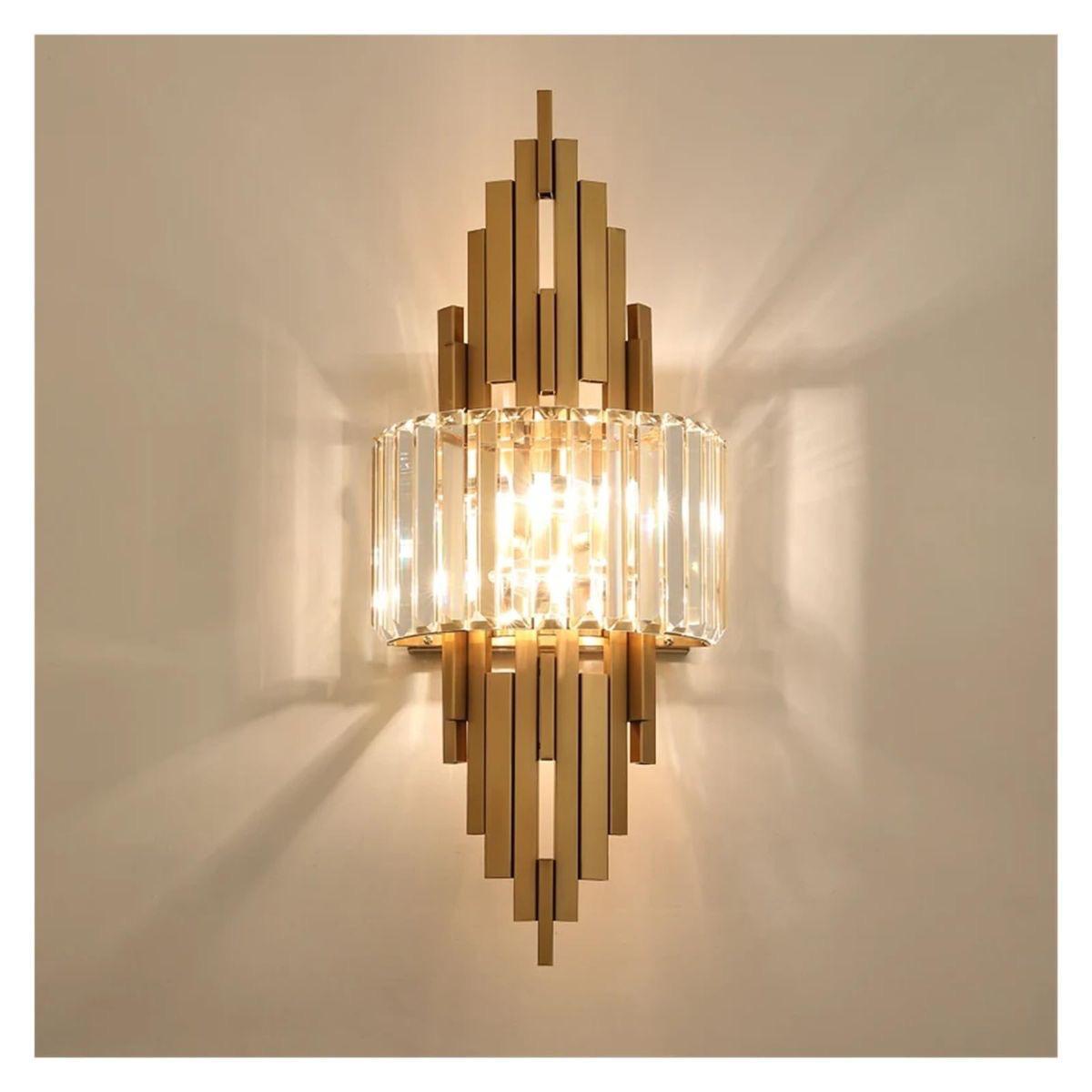 A lit gold and crystal wall sconce mounted on a neutral wall, casting a warm ambient glow.
