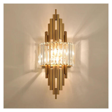 A lit gold and crystal wall sconce mounted on a neutral wall, casting a warm ambient glow.
