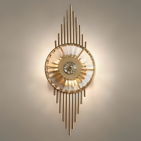 A luxurious gold and crystal wall sconce with vertical metal rods extending above and below a central circular light fixture, emitting a soft glow.