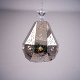 A geometric, faceted metal pendant light with reflective surfaces and decorative patterns, displayed against a soft background.
