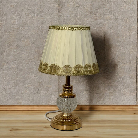 Ornate gold and cream table lamp with decorative gold lace trim on the fabric lampshade.
