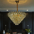 Gold chandelier hanging in a room with dark walls and plants.