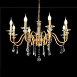 A gold chandelier with curved arms, crystal accents, and candle-shaped bulbs, set against a black background.