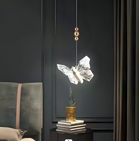 A stunning butterfly-shaped pendant light with a transparent, illuminated design hangs beside a bed, creating an elegant and artistic bedside lighting fixture.