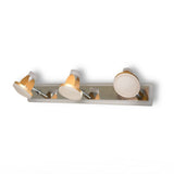 A contemporary three-light wall fixture with a polished metal base, featuring white and gold adjustable lampshades shaped like small spotlights.