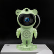 Green robot toy with a black screen on a white platform against a black background