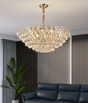 Chandelier hanging above a black sofa in a room with curtains and a plant.