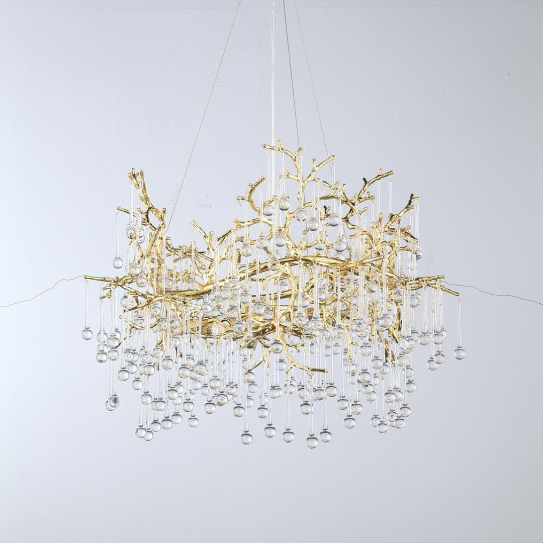 A luxurious gold chandelier with intricate branch-like detailing and hanging crystal drops.