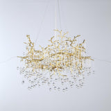 A luxurious gold chandelier with intricate branch-like detailing and hanging crystal drops.