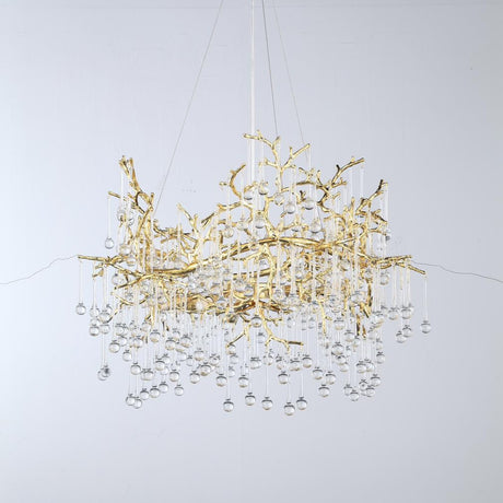 A luxurious gold chandelier with intricate branch-like detailing and hanging crystal drops.
