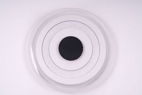  Circular flush mount ceiling light with a layered design of three concentric white rings surrounding a black center, emitting soft white light.