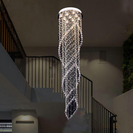 Tall spiral crystal chandelier in chrome finish hanging from a double-height ceiling in a staircase foyer.