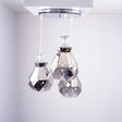 Three crystal-like teardrop pendant lights hanging from a chrome ceiling mount.