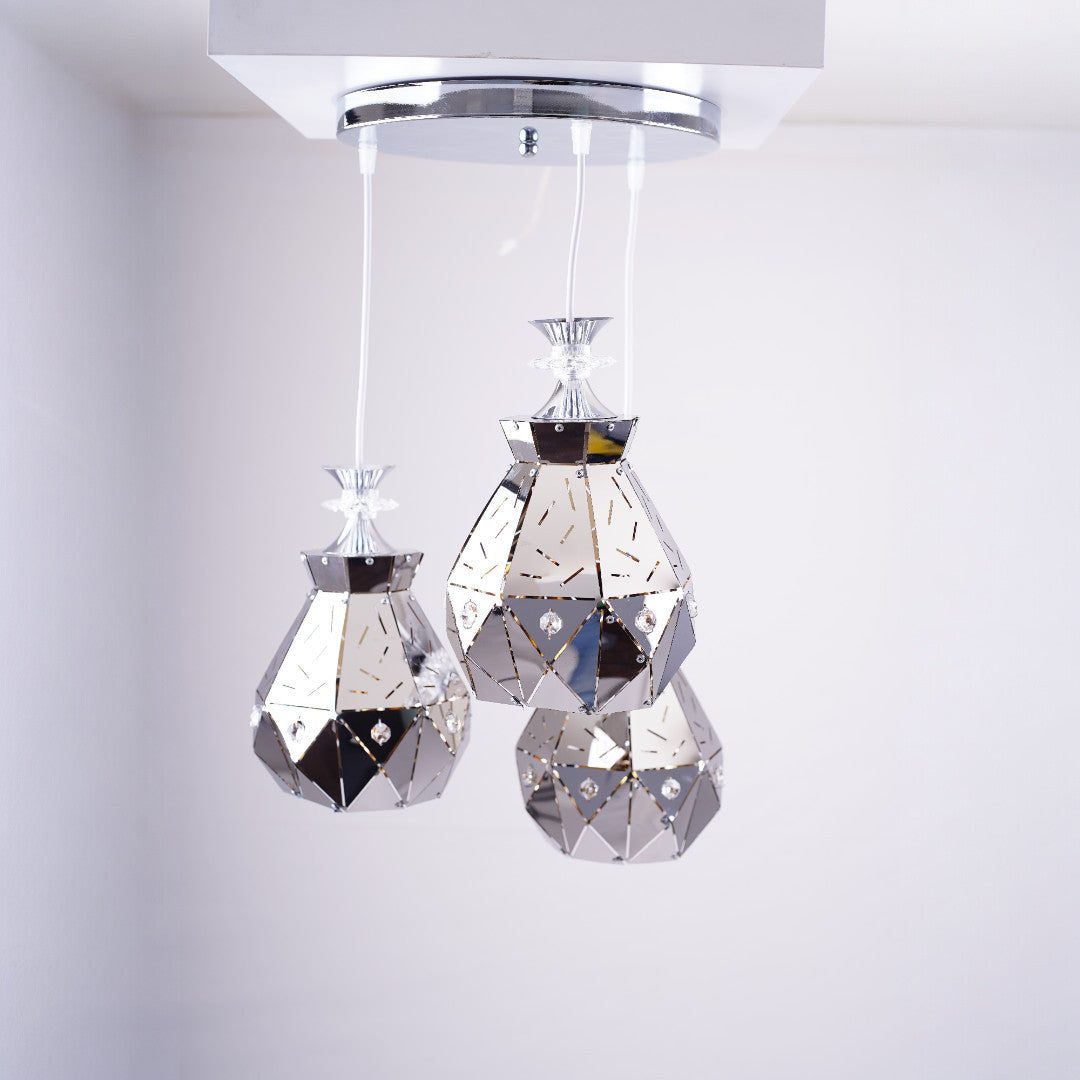 Three crystal-like teardrop pendant lights hanging from a chrome ceiling mount.