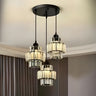 A modern chandelier with three black metal and glass pendant lights hanging from a black circular ceiling mount.
