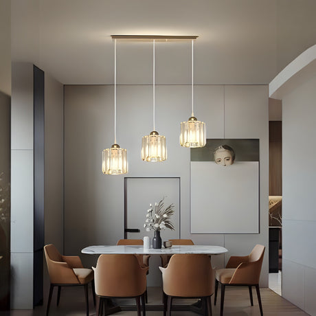 Three elegant ribbed glass pendant lights with gold details, suspended above a sleek white dining table in a modern interior.