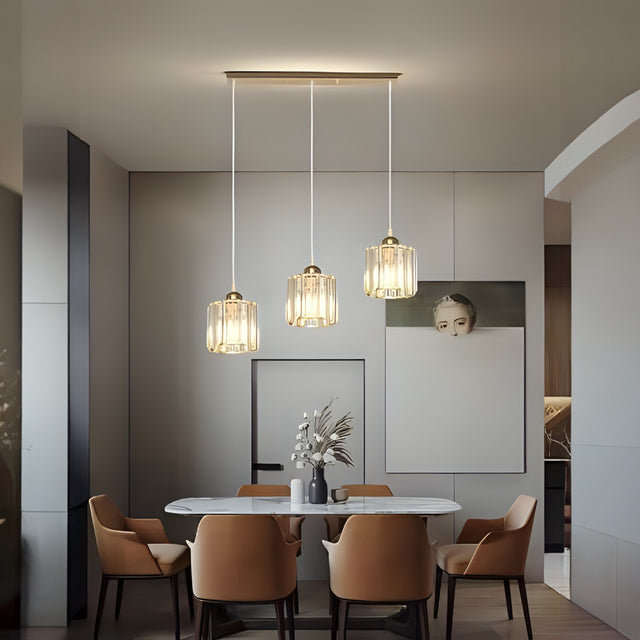 Three elegant ribbed glass pendant lights with gold details, suspended above a sleek white dining table in a modern interior.