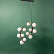 A gold chandelier with two curved metal arms, each adorned with frosted white glass globe lights, suspended from a black ceiling mount against a green background.
