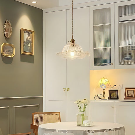 A vintage-style glass pendant light with gold accents hanging above a round dining table in a cozy kitchen space.
