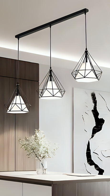 A set of three wireframe pendant lights with geometric metal frames hang at different heights.