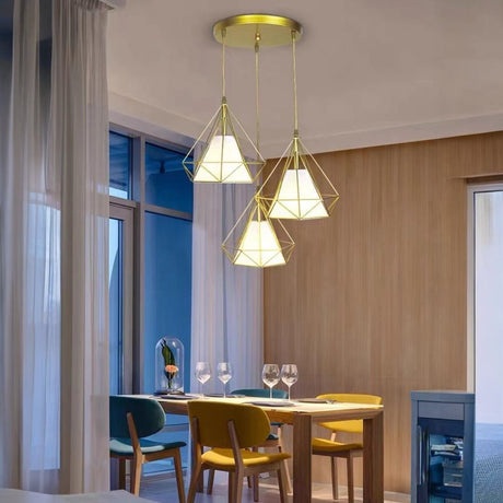 A cluster of golden triangular pendant lights suspended from a circular gold ceiling mount, positioned above a dining table with colorful chairs.