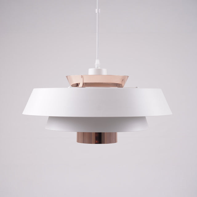A modern layered pendant light with a matte white and copper finish, featuring a wide circular design with concentric discs, hanging from a black cord against a light gray background.