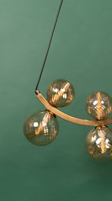 A detailed close-up of the gold chandelier’s glass globes, showcasing the led lamps reflections.
