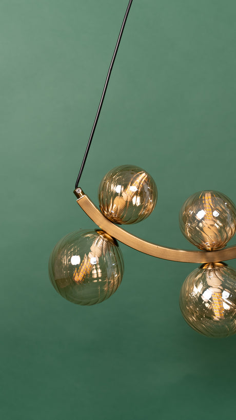A detailed close-up of the gold chandelier’s glass globes, showcasing the led lamps reflections.
