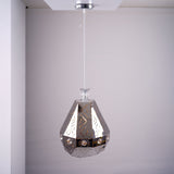 A geometric, faceted metal pendant light with reflective surfaces and decorative patterns, hanging from the ceiling.
