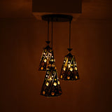 The black and gold pendant light cluster, glowing warmly in a dimly lit room.
