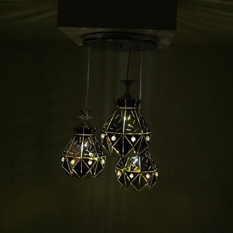 three crystal-like pendant lights glowing in the dark, creating a warm, geometric illumination.